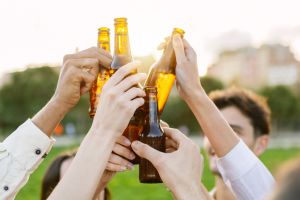Group of young people having fun drinking beer at summer party outdoors