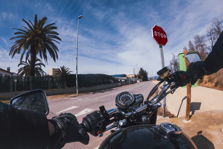 Riding an old black motorbike starting on a crossroad with stop signal