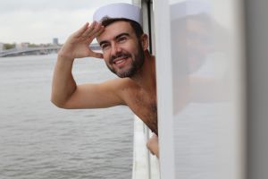 Shirtless sailor looking at the horizon in deck