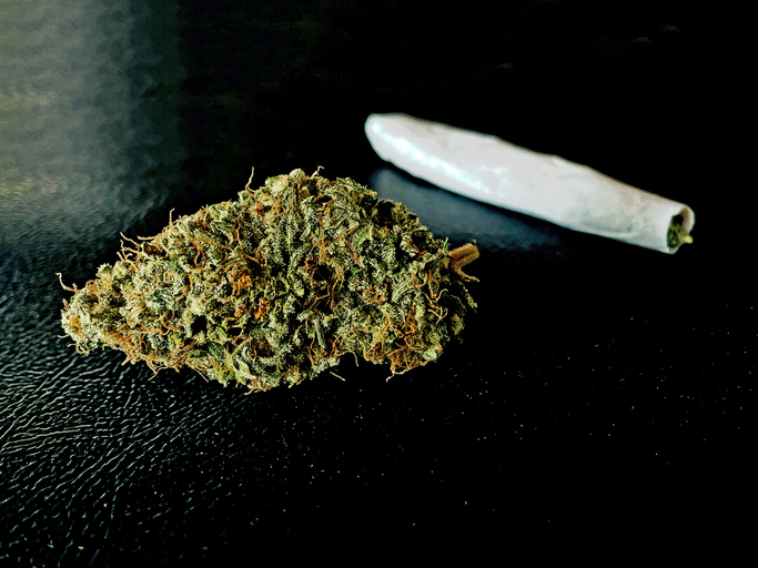 Cannabis bud and Marijuana joint rolled over balck background