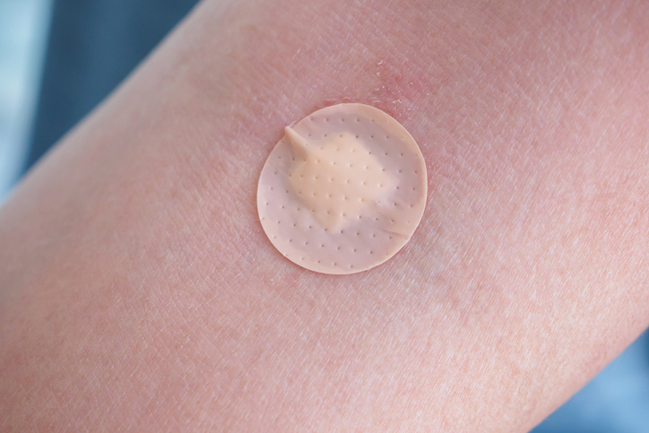 Round adhesive plaster on man arm close up