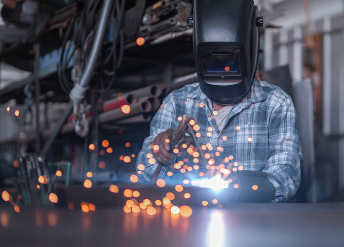 Male welder welding working in the workshop with welding torch repairing