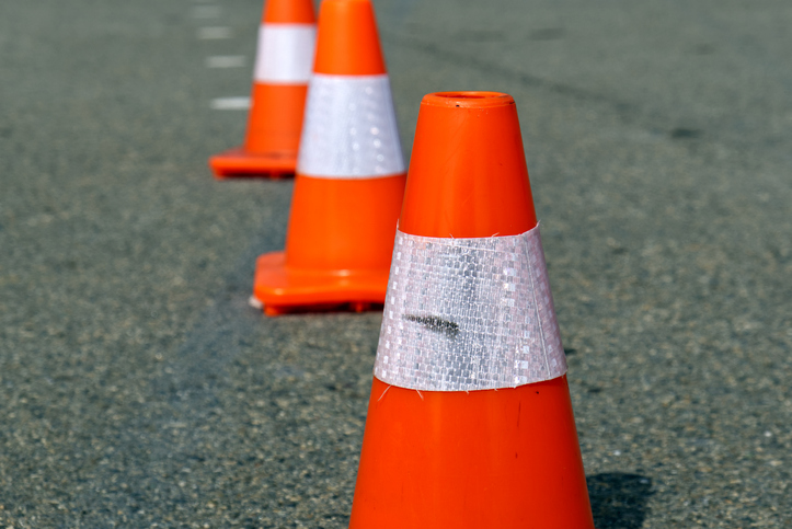 bright orange traffic cones standing in a row on dark asphalt