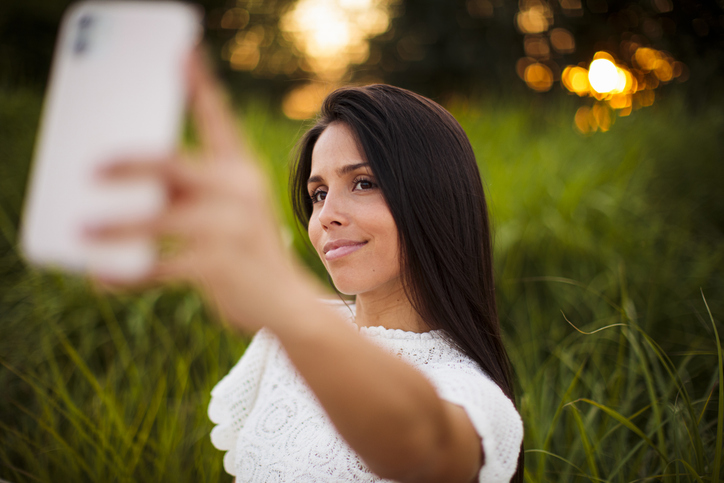 Portrait of young girl taking a selfie with mobile phone in public park