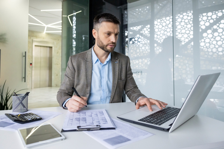 Businessman working with laptop and documents in modern office