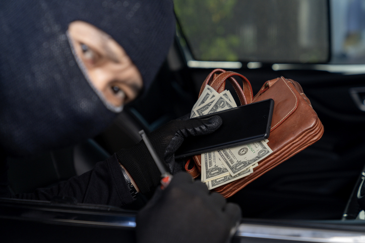A thief is stealing valuables from a car