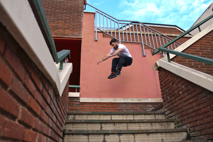Caucasian man doing parkour taking a mid-air jump