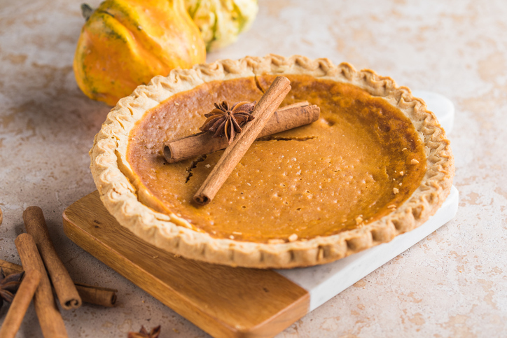 A while Fresh Baked Pumpkin Pie on a brown wooden table. Pumpkin Pie is enjoyed world wide for holidays and special events.