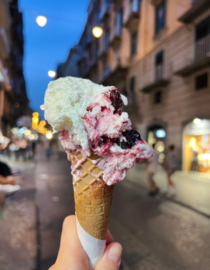 Woman hand holding an ice cream cone on a night street
