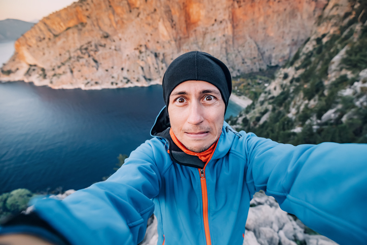 Hiker man is experiencing a panic attack due to fear of heights and phobia. Accident outdoors