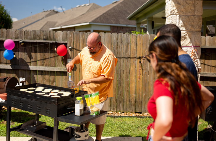 Man making tacos on the grill while having a family party outdoors