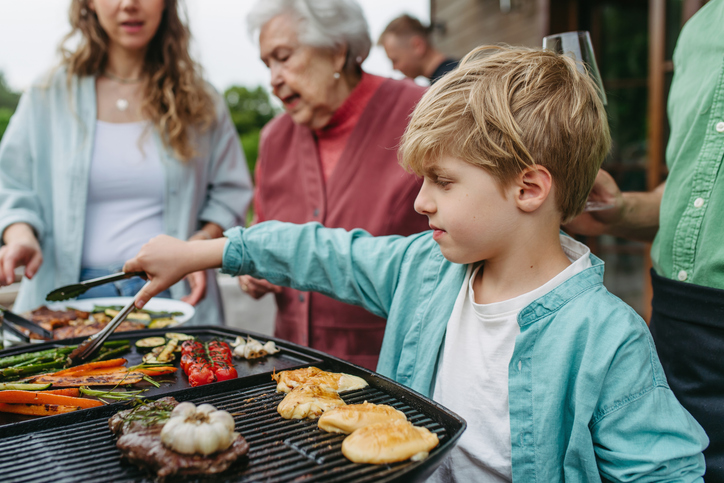 Family barbecue in backyard. Multigenerational family come together, enjoying grilled food and spending quality time outdoors together.