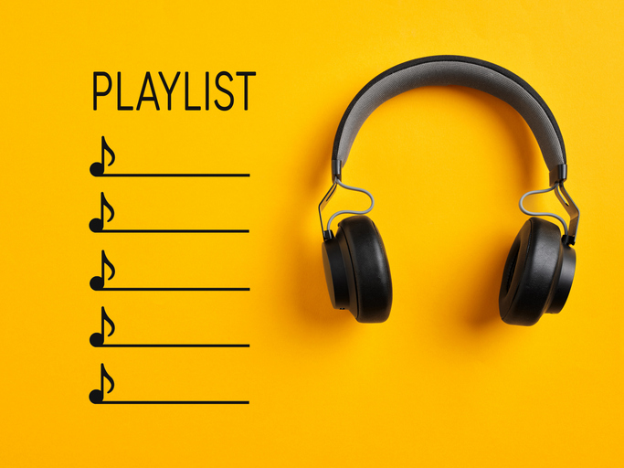 Playlist and listening to music. Black wireless headphone with playlist on yellow background.