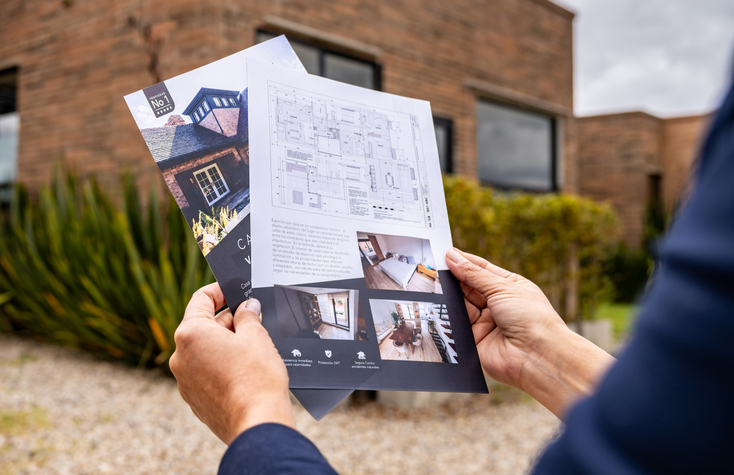 Real estate agent holding brochures of a house for sale