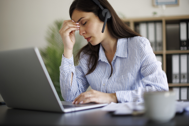 Tired businesswoman with headset having a headache from working at office