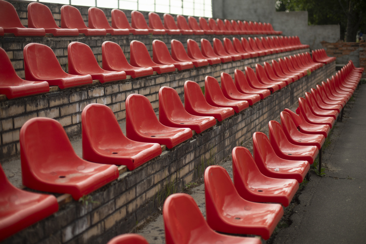 The grandstand at the sports arena. Empty seats in the stadium. Red plastic chairs.