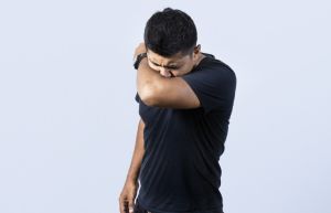 People sneezing with his elbow, A guy sneezing with his elbow on isolated background, concept of man having a cold sneezing with his elbow
