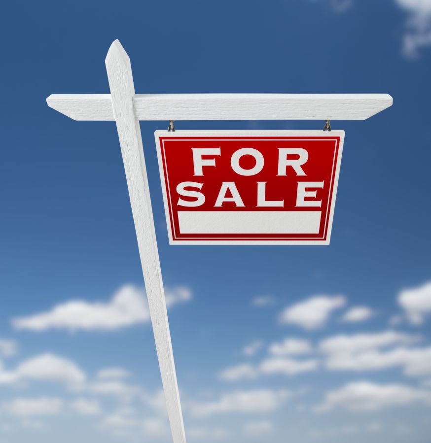 Right facing for sale real estate sign on a blue sky with clouds