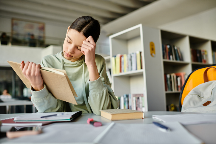Teenage girl immersed in homework at a cozy library after school hours