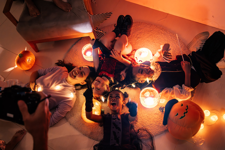 Cheerful family lies on the floor with pumpkins for the Halloween holiday in a cozy house