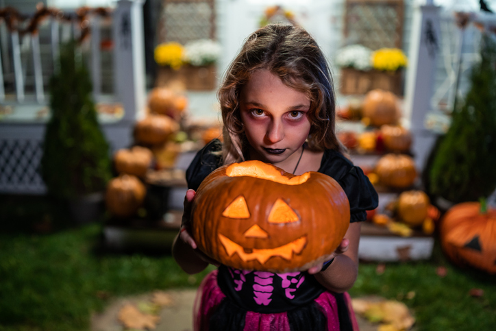 Girl holding Jack-o-Lantern Pumpkins on Halloween trick or treat
