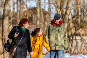 Winter family interaction. Autistic son communicates with his sister as mother - photographer, captures their snowy walk in the park.