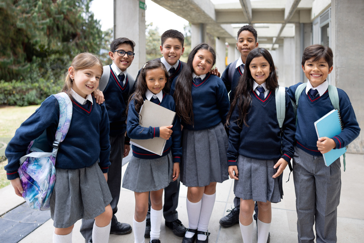 Happy group of elementary students smiling at the school