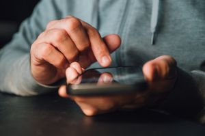 Doomscrolling or doomsurfing concept, closeup of male hands using smartphone
