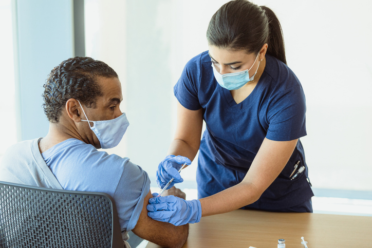 Female nurse administers vaccine to male doctor