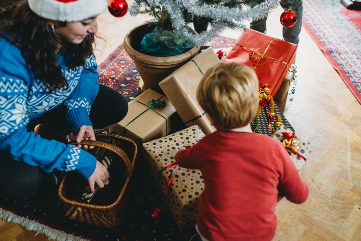 Mother and son arranging christmas presents under decorated tree