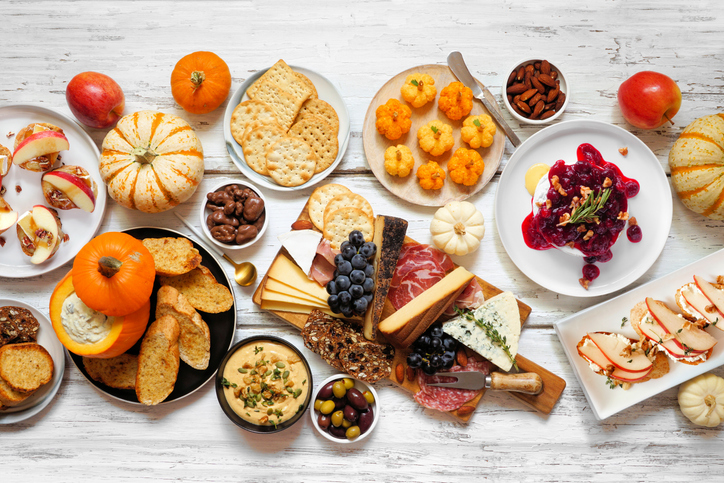 Autumn theme appetizer table scene against a white wood background