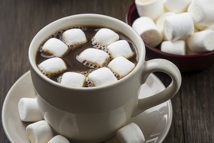 A ceramic cup filled with a hot chocolate adorned with several white marshmallows