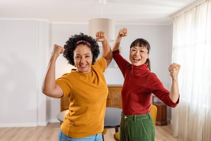 Two women laughing and flexing muscles - Girl power