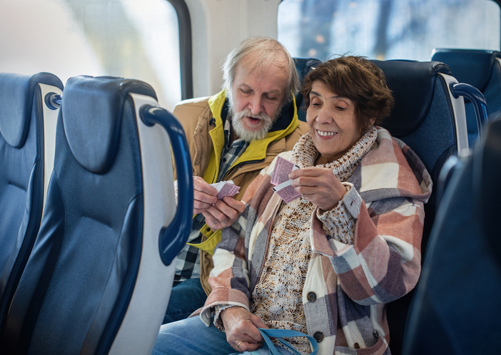 Train travelers engage with technology. Senior couple looking at tickets during journey from New Jersey to NYC.