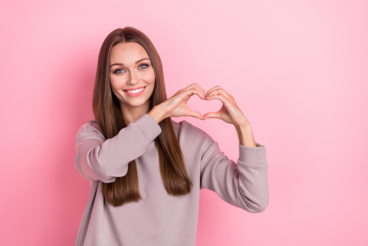 Photo of lovely sweet lady wear stylish sweater arm show love sign symbol gesture empty space isolated on pink color background