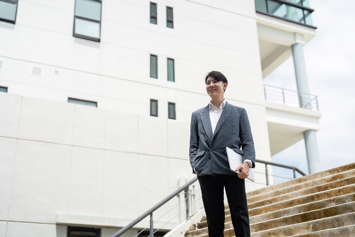 Confident Businessman with Laptop at Modern Office Building Entranc
