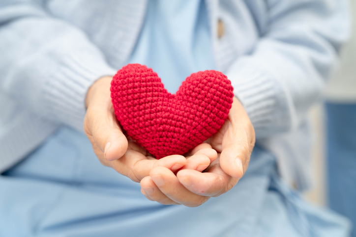 Asian elder senior woman patient holding red heart in hospital.