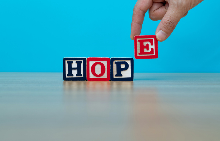 Human hand spelling word hope with toy blocks