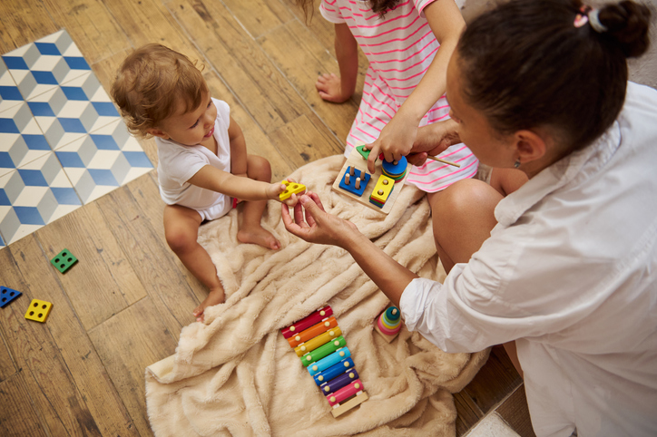 Mother and children playing with colorful wooden toys at home