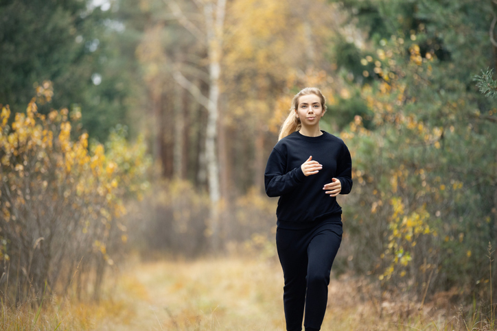 A beautiful woman jogging, enjoying nature looks around and listens to the surrounding autumn forest