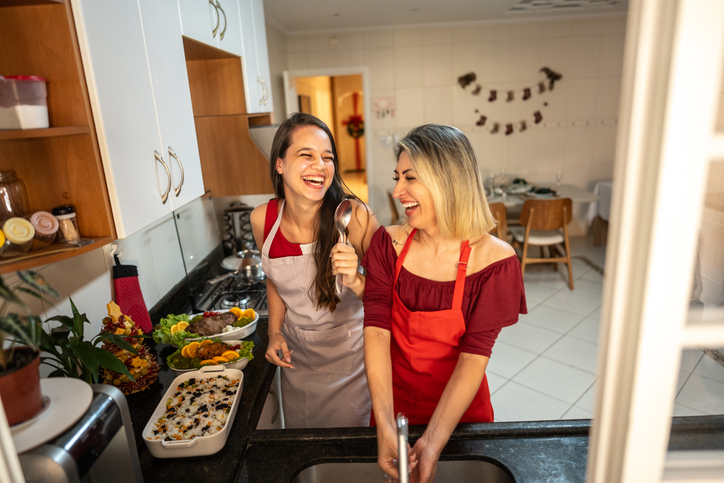 Mother and daughter singing and cooking for Christmas on kitchen at home