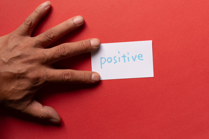 A person holding a card that says "positive"