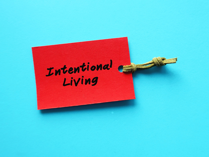 Red paper tag on blue background with handwritten words INTENTIONAL LIVING, means understanding fundamental beliefs and values and making decision to live everyday for those values actively
