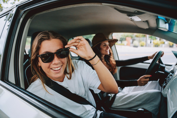 Two friends traveling by car wearing sunglasses