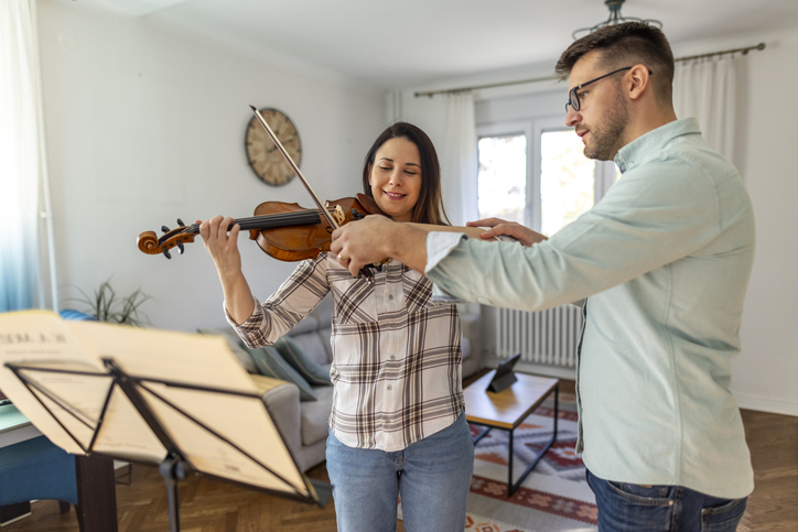 Young Woman Learning to Play Violin With Instructor at Home
