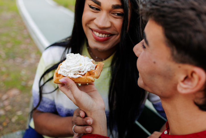 Latin transgender woman sharing waffle with partner in park