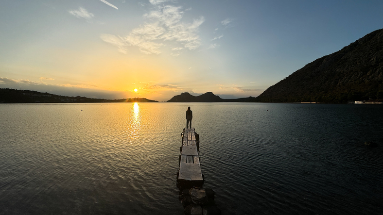 Embracing Freedom: Woman Standing on Pier at Sunset - stock photo