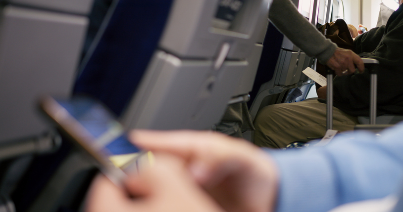 Cinematic video: Tourists boarding plane and hide luggage. People are boarding plane and checking their phones. Concept: Turn off your phone after the boarding plane to safety flight. Airplane mode.