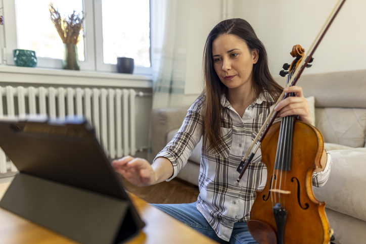Woman Learning Violin with Online Resources on a Tablet at Home