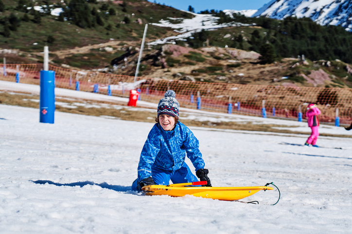 Cheerful boy kneeling near sleigh